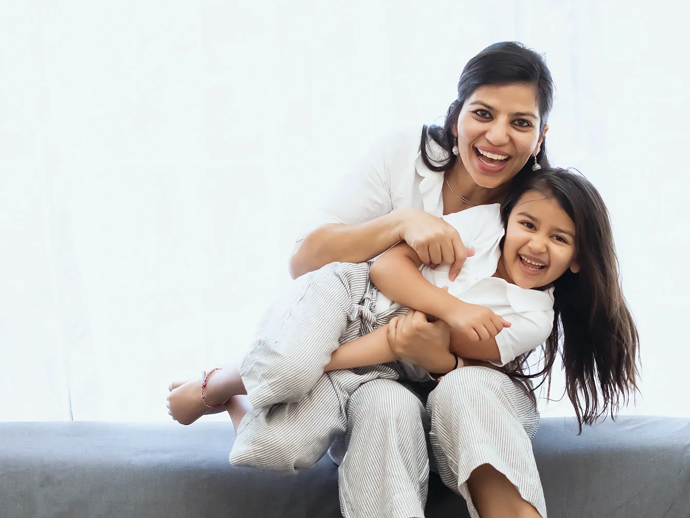 Mother and daughter laughing together on a sofa