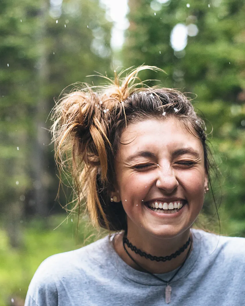 Young woman laughing outdoors among trees