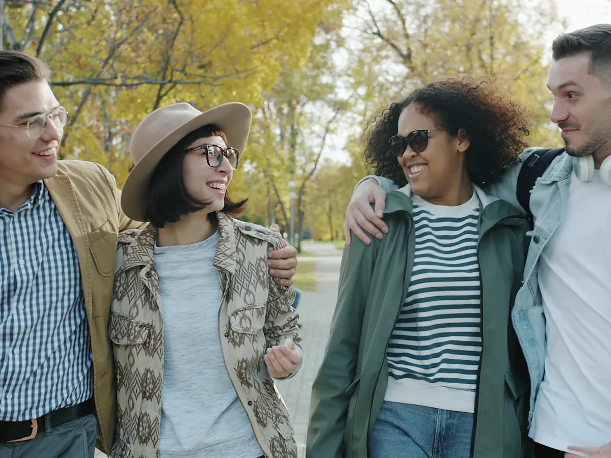 Four friends walking and laughing in a park