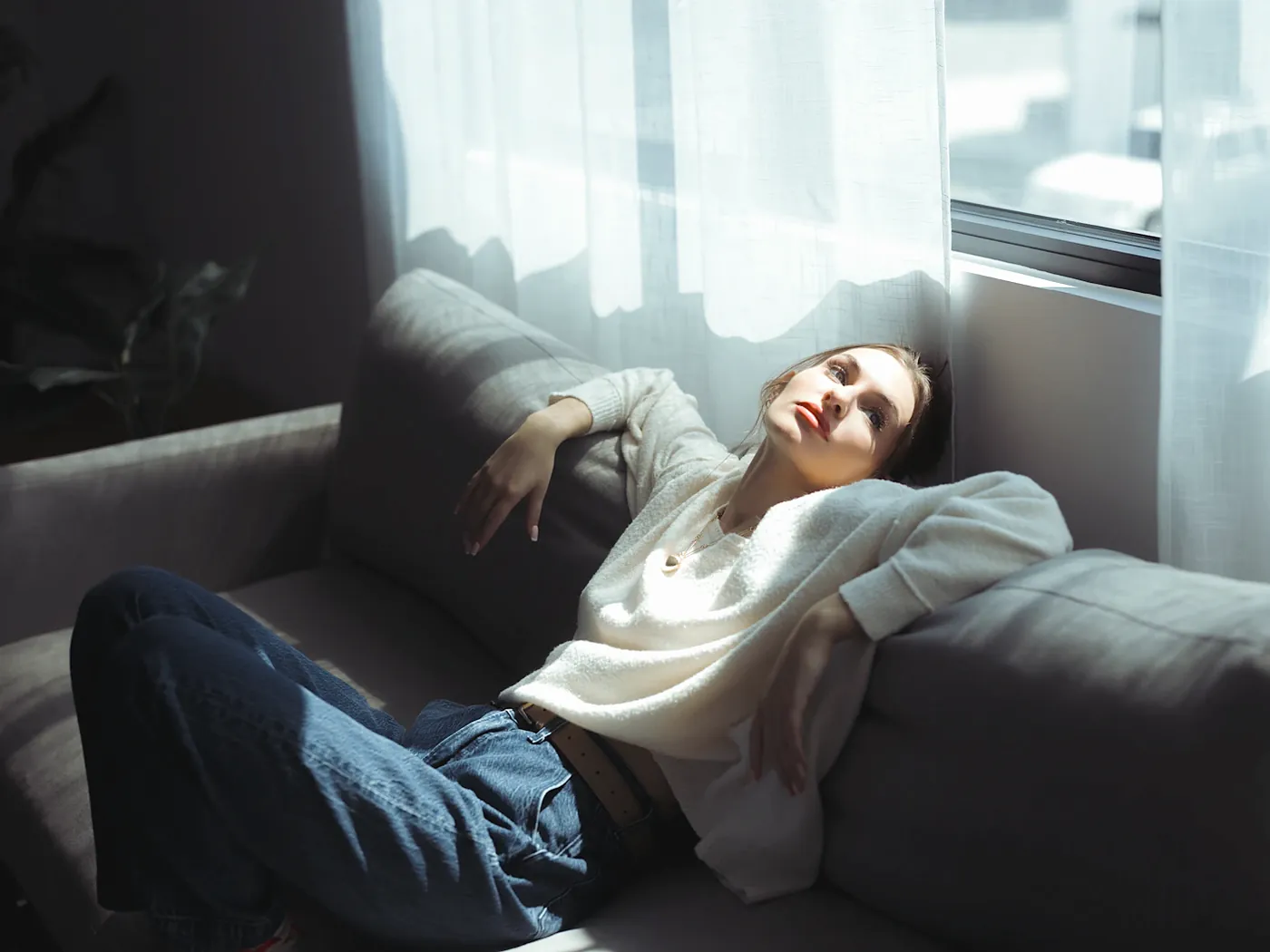 Woman resting in warm window light, looking up hopefully